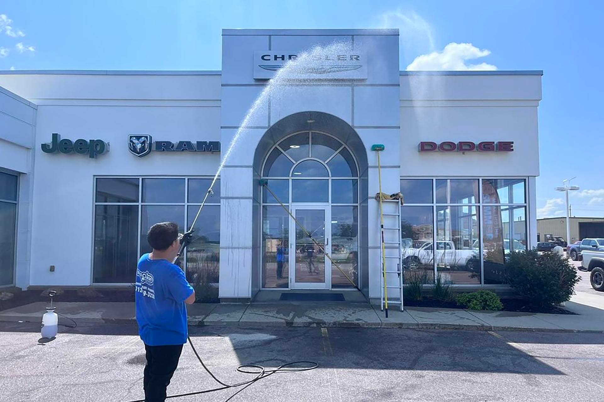 Pro clean mobile wash soft washing a car dealership exterior building.