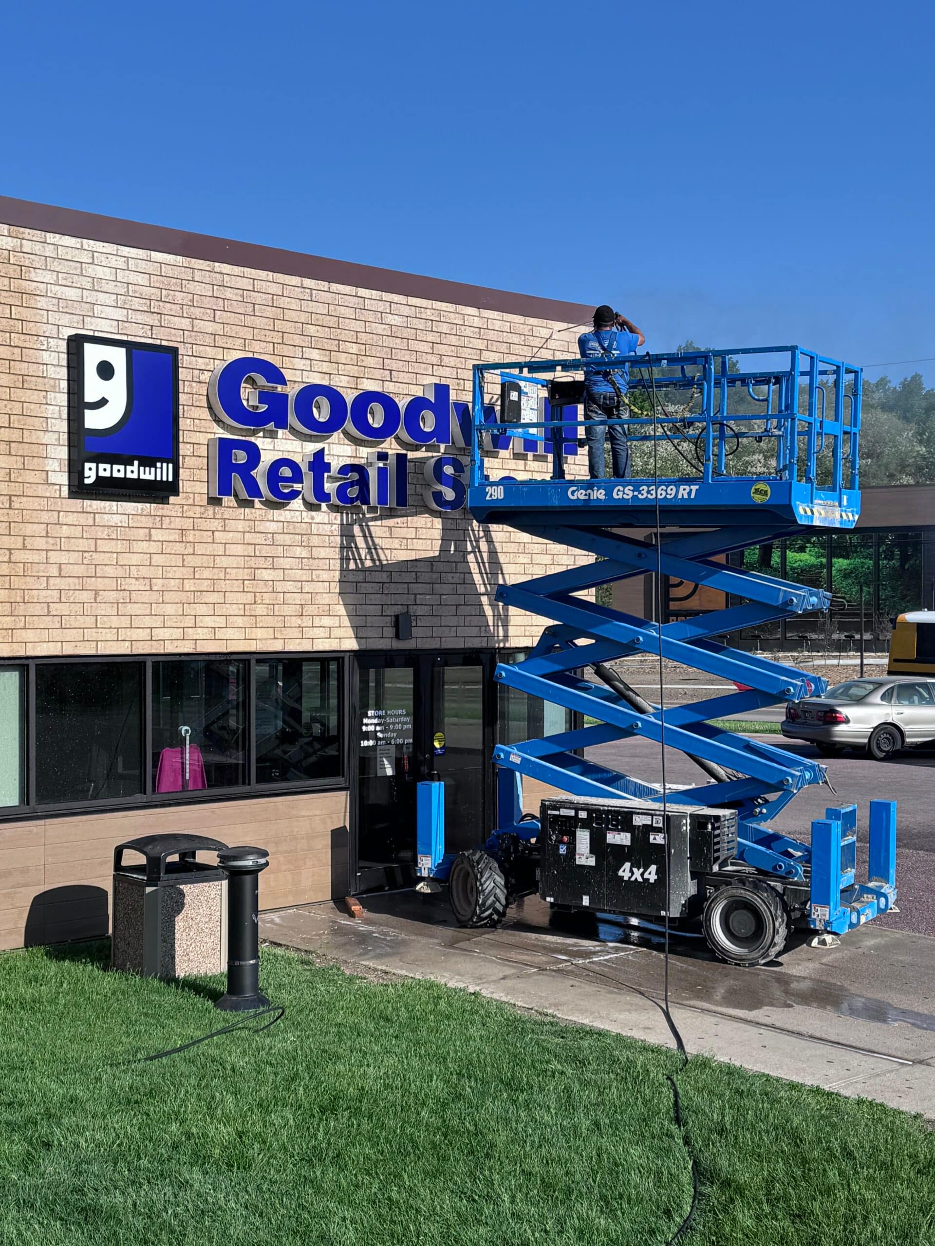 Pro clean mobile wash tech power washing a Goodwill commercial retail storefront